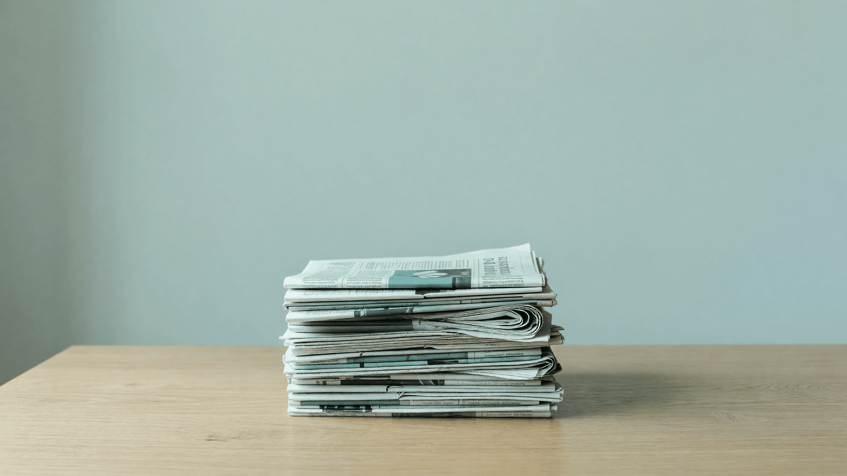 A quiet stack of trade newspapers on a desk — the source stack behind nuclear energy news in 2026. Illustration: NNN