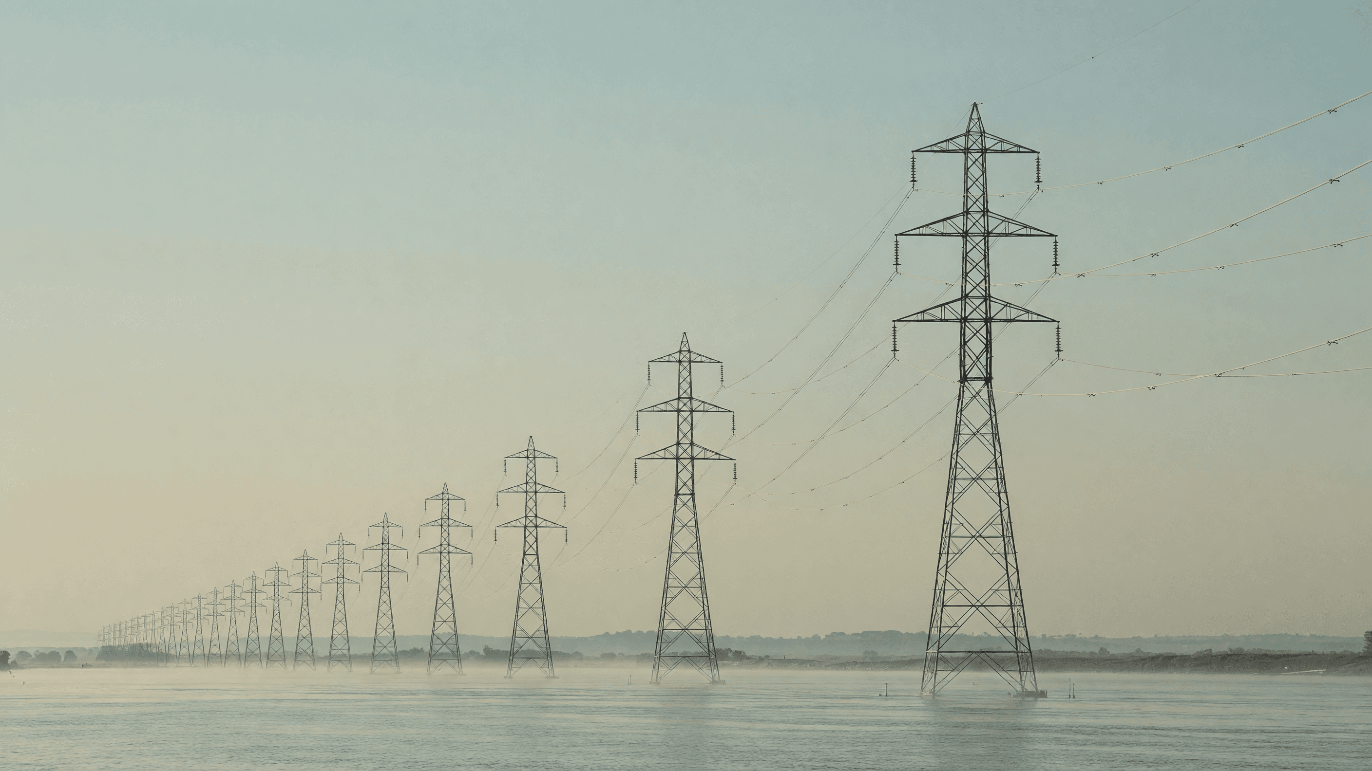 Transmission pylons cross a misty river valley at dawn — TVA's 2026 IRP leads today's brief. Illustration: NNN