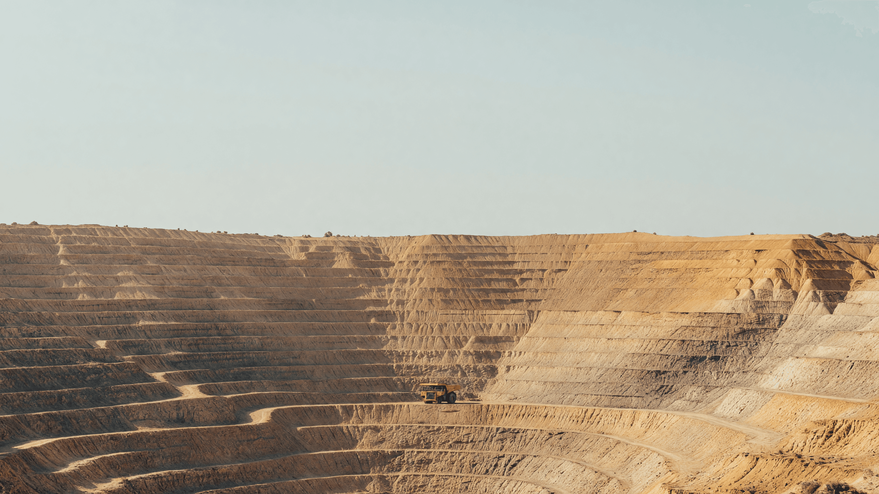 A haul truck dwarfed by an open-pit uranium mine's terraces — the India-Australia export pact leads today's brief. Illustration: NNN