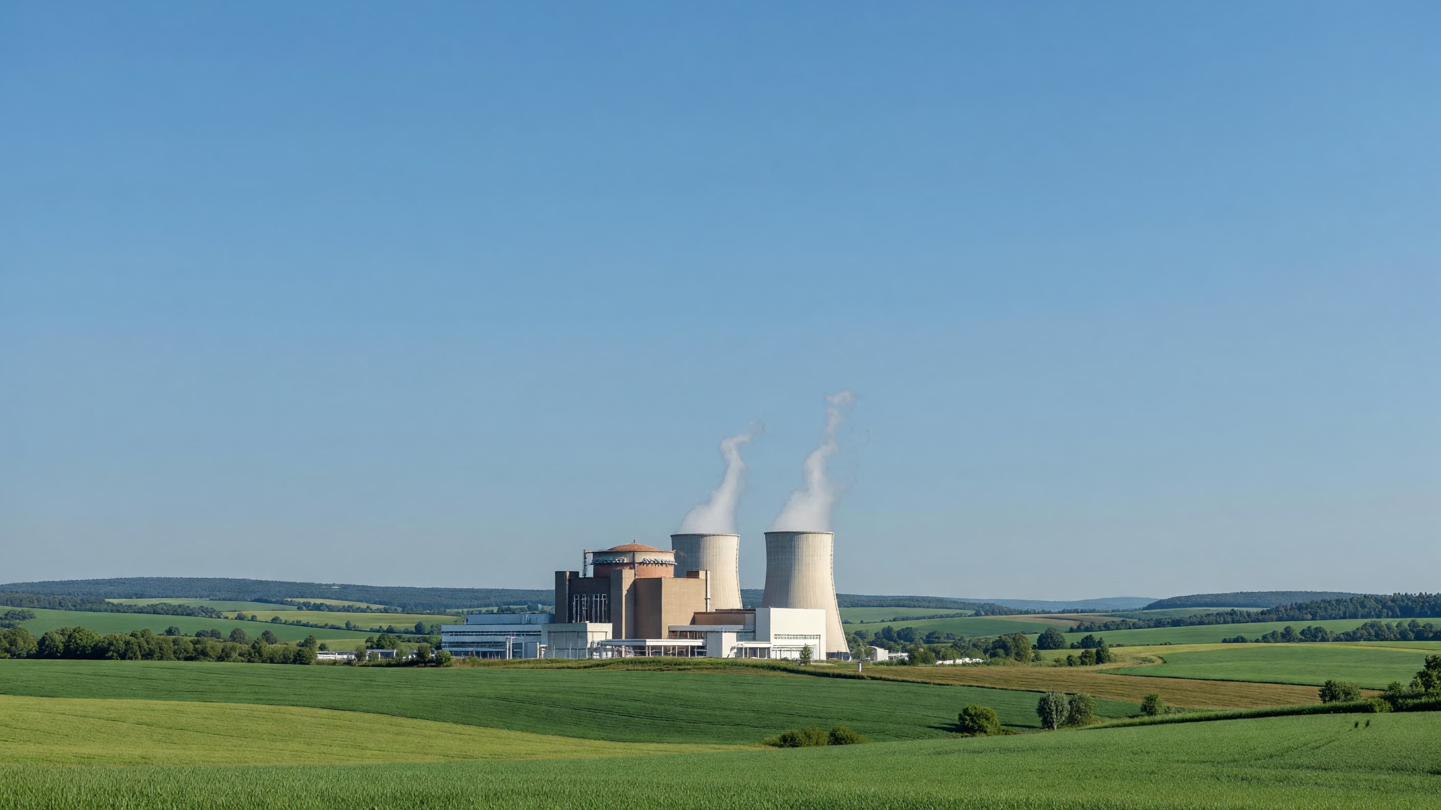 A European nuclear power plant with cooling towers in green rolling farmland under a clear blue sky, representing Mochovce Unit 4 preparing for start-up tests. Illustration: NNN