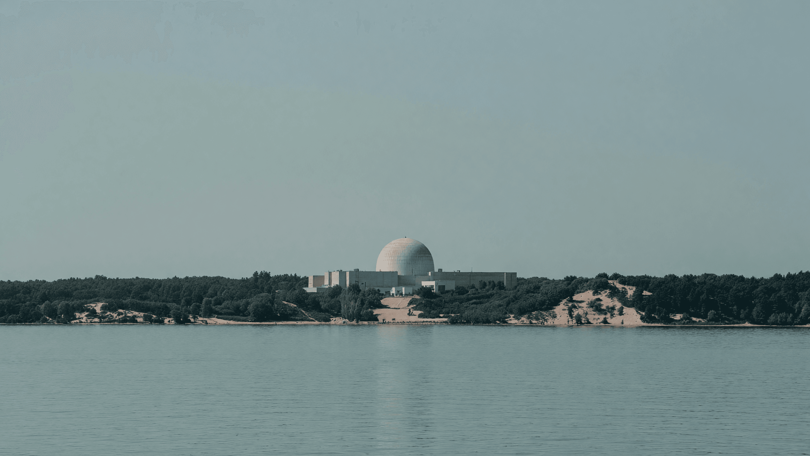 The Palisades dome on Lake Michigan's wooded dune shoreline — the site where Holtec plans its two SMR-300 Pioneer units. Illustration: NNN