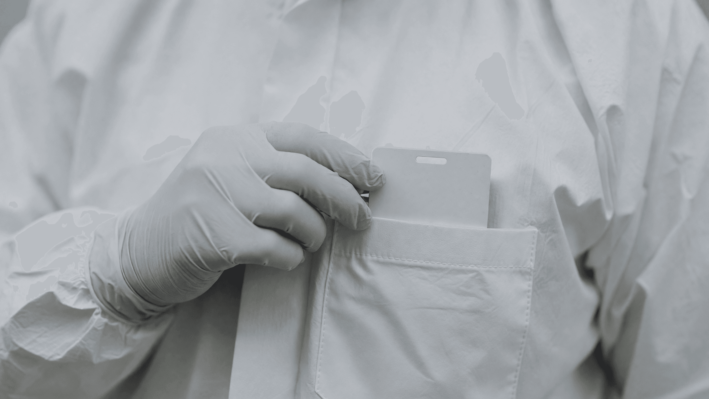 A gloved hand slips a dosimeter badge into a coverall chest pocket — the instrument at the centre of the ALARA rewrite. Illustration: NNN