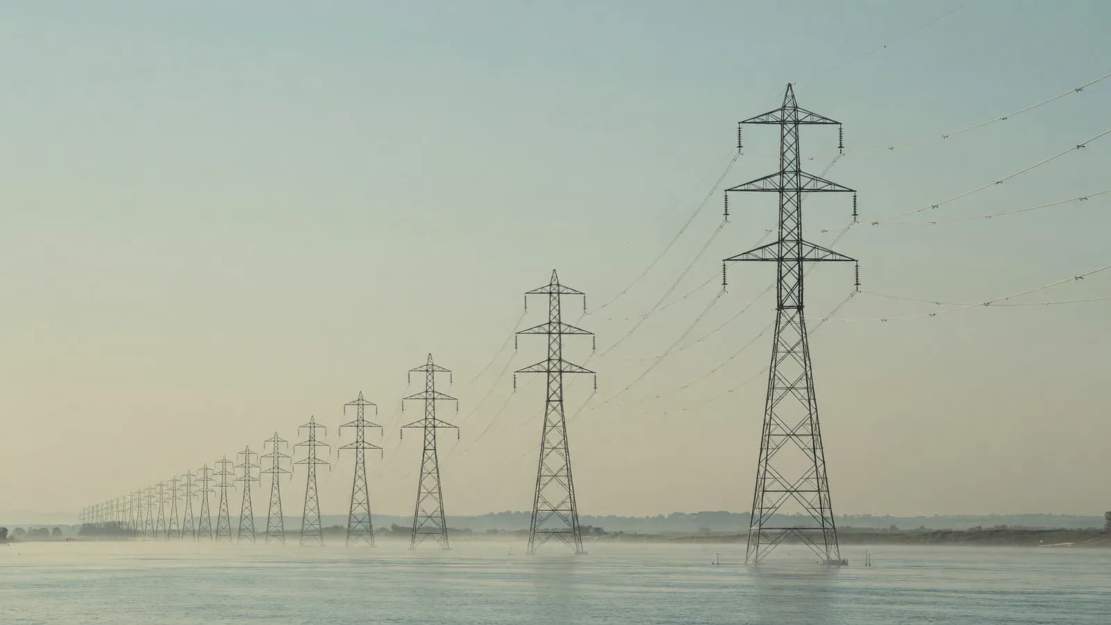 Transmission pylons cross a misty river valley at dawn — TVA's 2026 IRP leads today's brief. Illustration: NNN