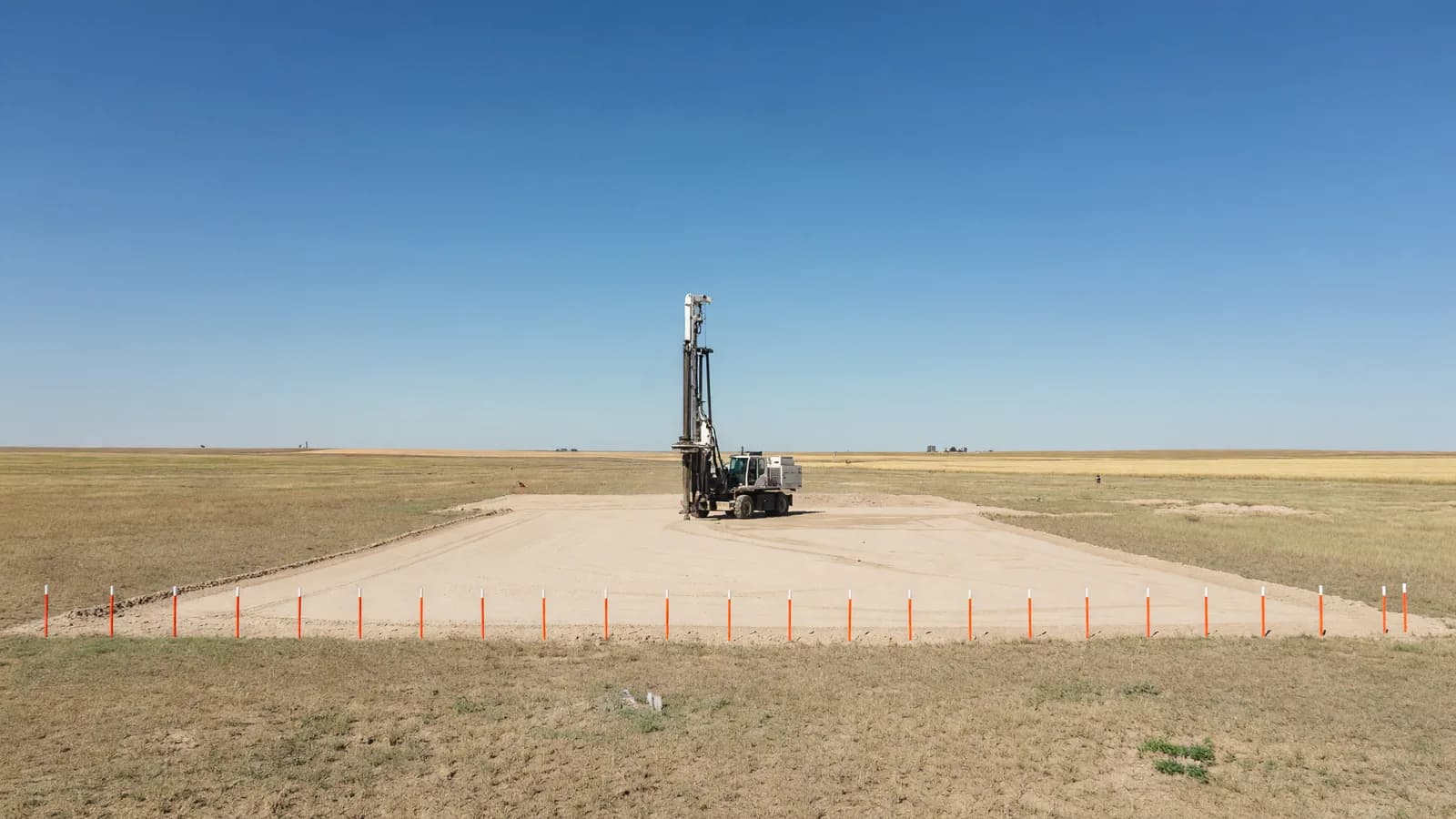 A graded construction pad and a soil-boring drill rig on flat Texas Panhandle prairie, the kind of site where Fermi America proposes four AP1000 reactors near Amarillo. Illustration: NNN