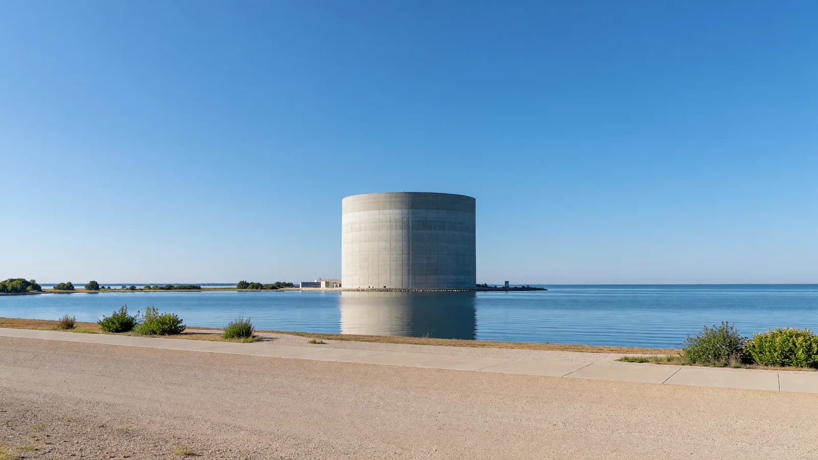 The Palisades reactor building beside Lake Michigan, representing the week's lead story: a pause in fuel loading after an assembly tilted inside the vessel. Illustration: NNN